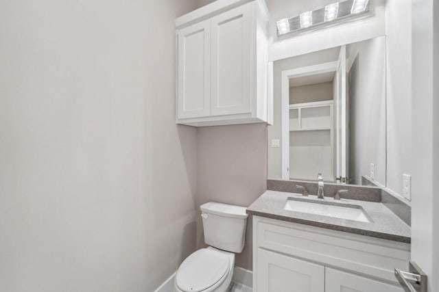 half bath with toilet, baseboards, and vanity