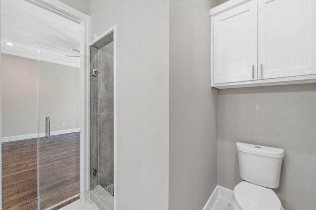 bathroom with a stall shower, toilet, and baseboards