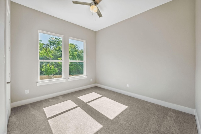 empty room with carpet flooring, a ceiling fan, and baseboards