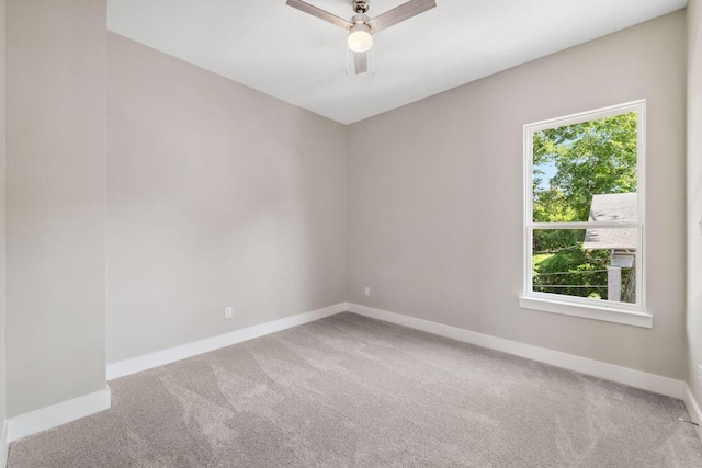 carpeted spare room featuring ceiling fan and baseboards