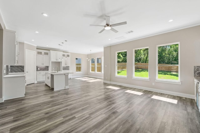 unfurnished living room featuring baseboards, visible vents, a sink, and wood finished floors