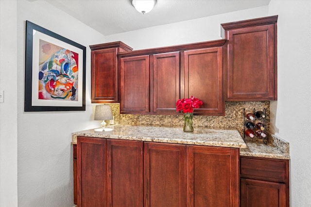 interior space featuring reddish brown cabinets, backsplash, and light stone countertops