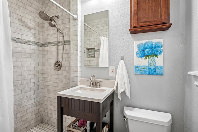 bathroom featuring a tile shower, vanity, and toilet