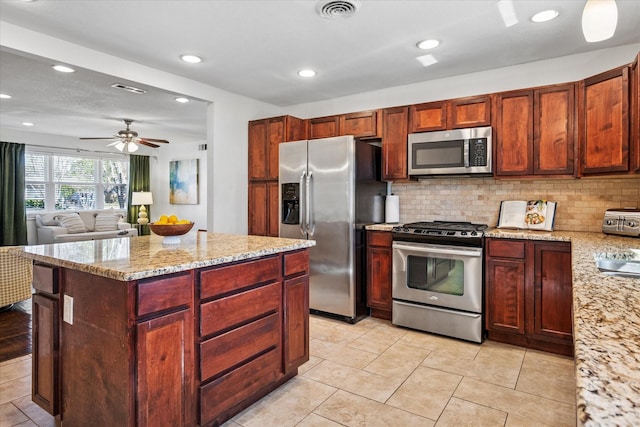 kitchen with light stone countertops, visible vents, stainless steel appliances, and backsplash