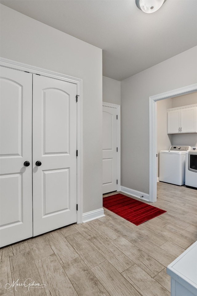 interior space featuring independent washer and dryer, light wood-type flooring, and baseboards