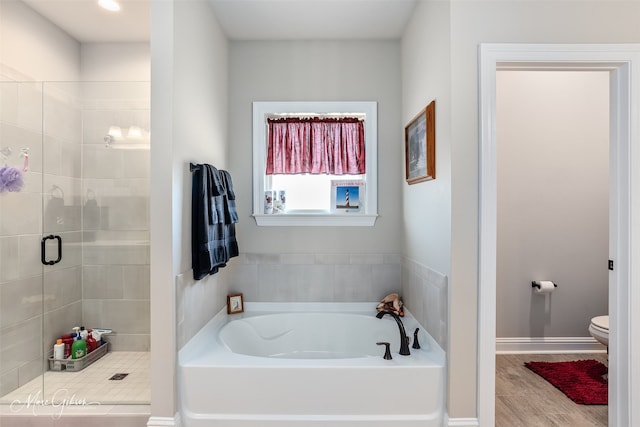 full bath featuring toilet, a shower stall, wood finished floors, baseboards, and a bath