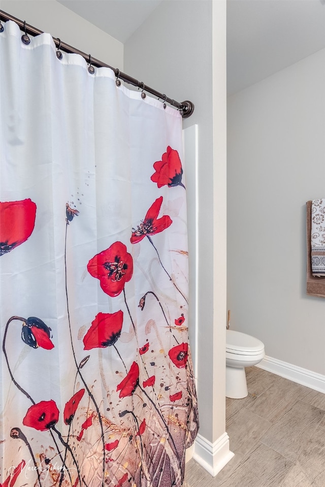 full bath with a shower with shower curtain, toilet, and baseboards