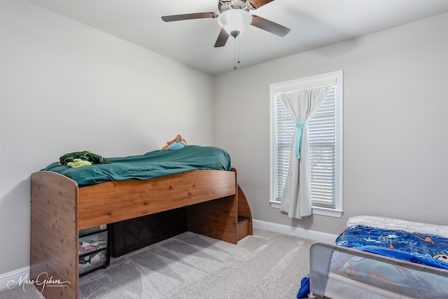 carpeted bedroom with ceiling fan and baseboards