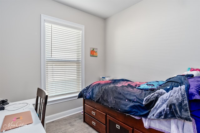 bedroom with light wood finished floors and baseboards