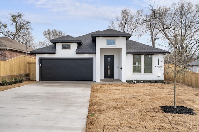 view of front of property with an attached garage, a shingled roof, fence, concrete driveway, and stucco siding