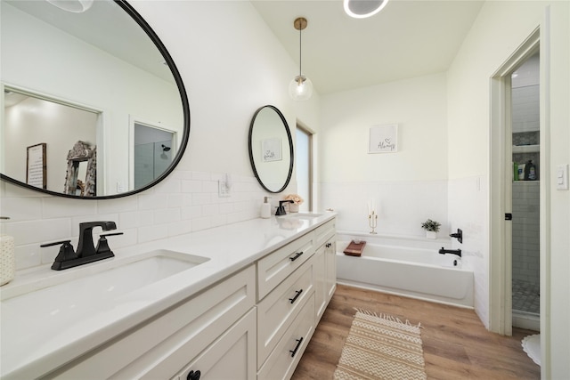 bathroom featuring double vanity, a sink, a bath, and wood finished floors