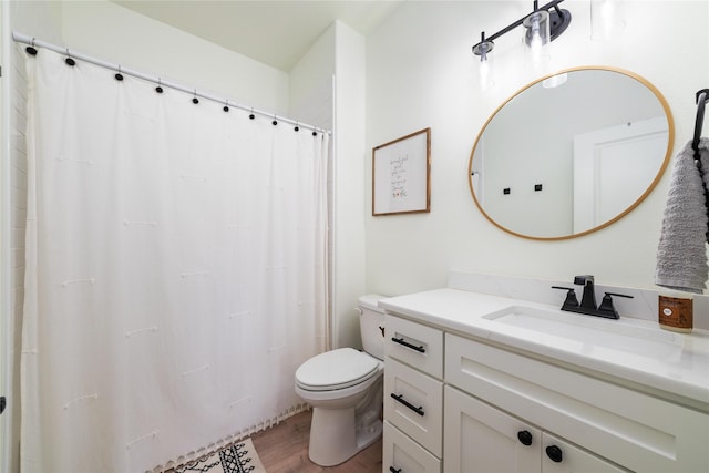 bathroom featuring toilet, a shower with shower curtain, wood finished floors, and vanity