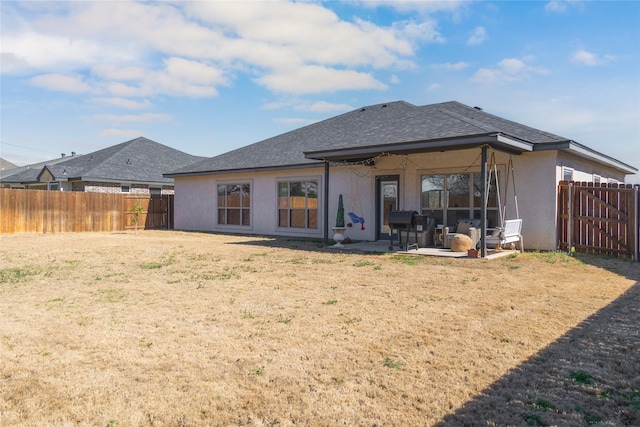 rear view of property featuring a shingled roof, a patio area, a fenced backyard, and stucco siding