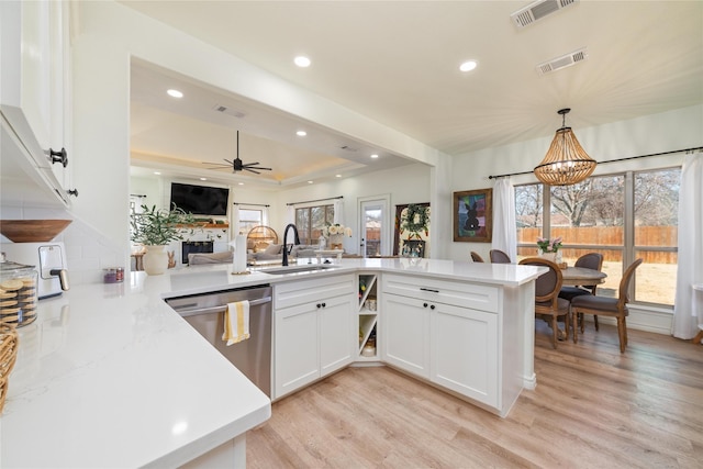 kitchen featuring light wood finished floors, visible vents, white cabinetry, a sink, and dishwasher