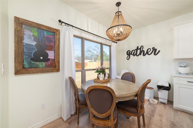 dining area with baseboards, light wood finished floors, and an inviting chandelier