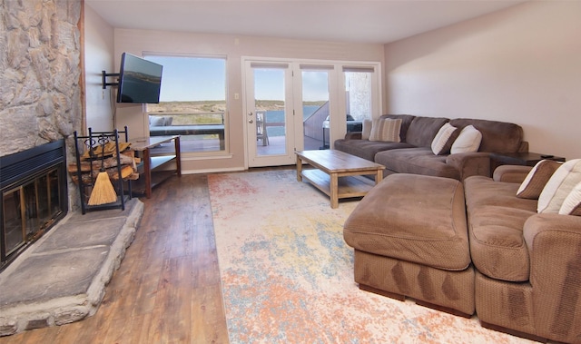 living area featuring a stone fireplace and wood finished floors