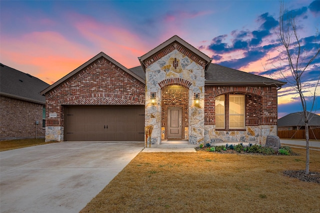 french country inspired facade featuring a garage, stone siding, and brick siding