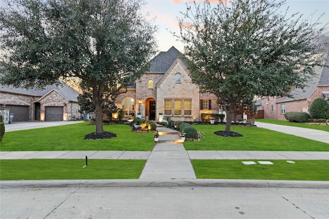 french country inspired facade featuring stone siding and a yard