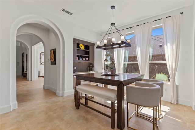 dining space featuring an inviting chandelier, baseboards, visible vents, and arched walkways