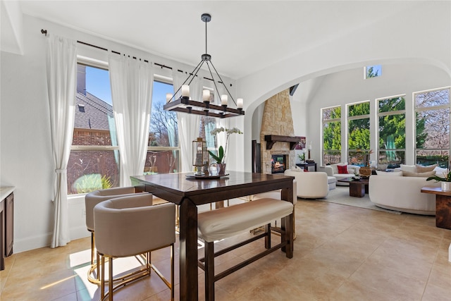 dining room with plenty of natural light, a fireplace, a notable chandelier, and light tile patterned flooring