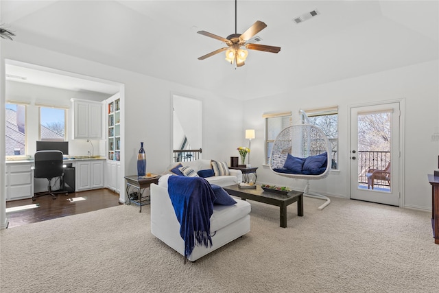 carpeted living area featuring a ceiling fan, visible vents, built in desk, and baseboards