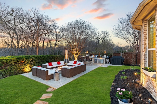 yard at dusk featuring fence, an outdoor living space, a patio, and area for grilling