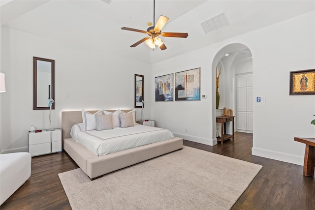 bedroom with arched walkways, dark wood-style flooring, visible vents, and baseboards