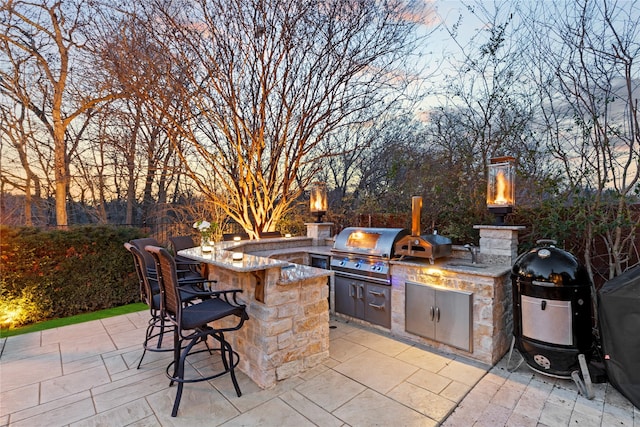 view of patio with exterior kitchen, area for grilling, a sink, and outdoor wet bar