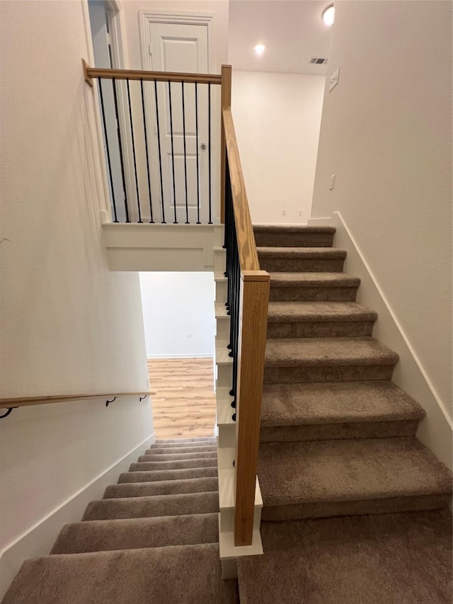 staircase with visible vents and wood finished floors