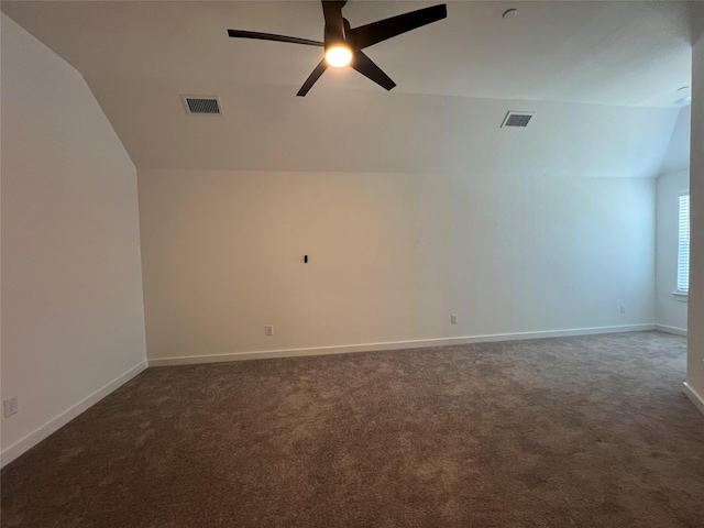 empty room with carpet, visible vents, lofted ceiling, and baseboards