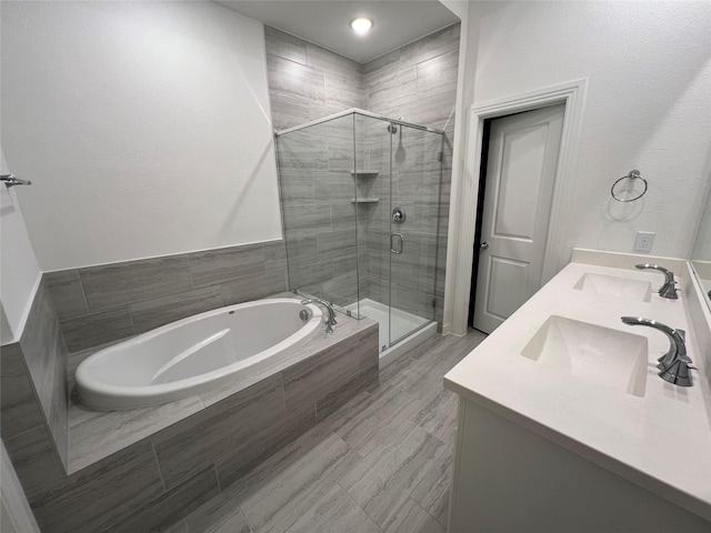 full bathroom with double vanity, a garden tub, a shower stall, and a sink