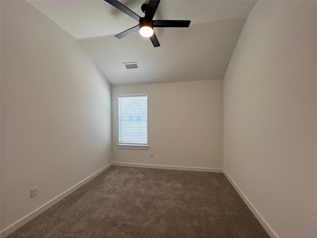 empty room with lofted ceiling, dark carpet, visible vents, and baseboards