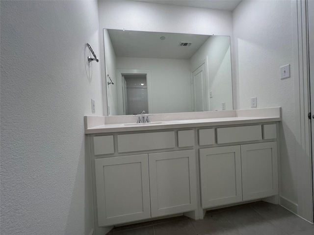 bathroom with visible vents, a textured wall, vanity, and tile patterned floors