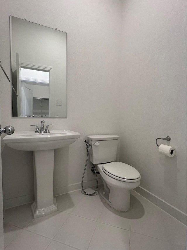 bathroom with tile patterned flooring, baseboards, a sink, and toilet