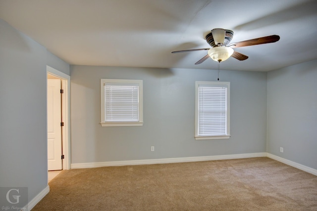 empty room featuring light carpet, baseboards, and a ceiling fan