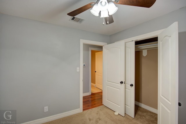 unfurnished bedroom with a closet, visible vents, light carpet, and baseboards