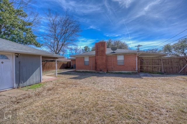 exterior space featuring a chimney, fence, a lawn, and brick siding