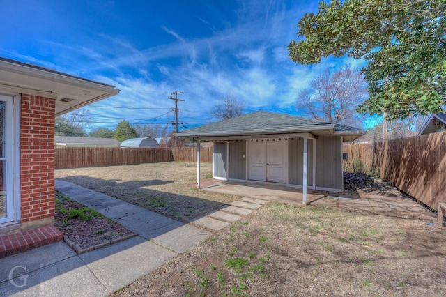 view of yard featuring an outbuilding, a fenced backyard, and a shed