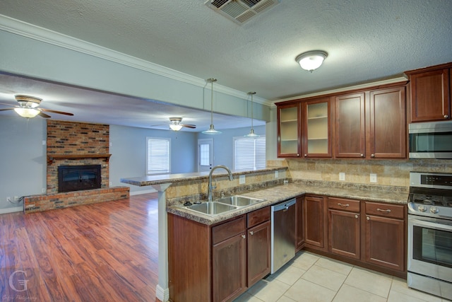 kitchen featuring visible vents, appliances with stainless steel finishes, open floor plan, a sink, and a peninsula