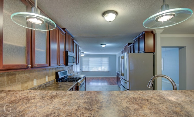 kitchen featuring stainless steel appliances, a sink, ornamental molding, backsplash, and glass insert cabinets