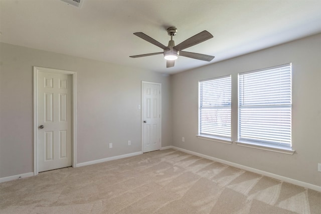 empty room with light carpet, ceiling fan, and baseboards