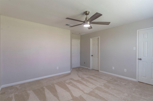 empty room with light carpet, visible vents, baseboards, and ceiling fan