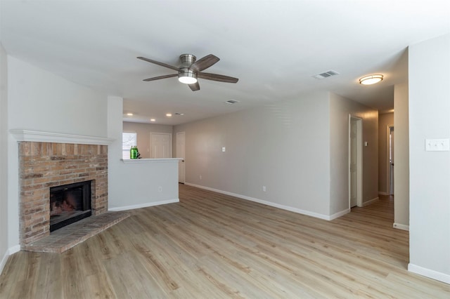 unfurnished living room featuring baseboards, a fireplace, visible vents, and wood finished floors