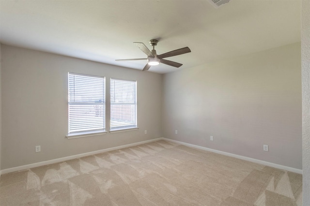 spare room with a ceiling fan, light colored carpet, and baseboards