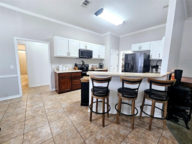 kitchen featuring a peninsula, visible vents, white cabinets, light countertops, and black appliances