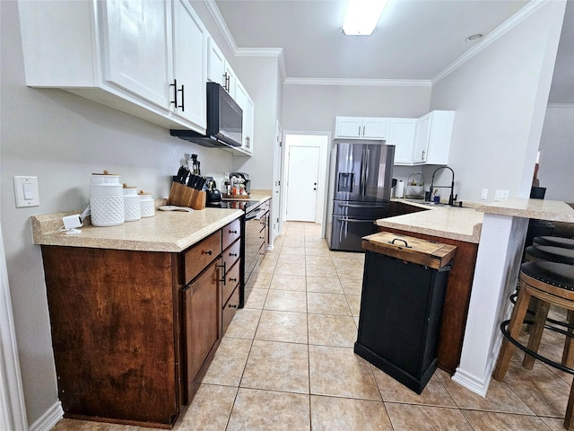 kitchen featuring a breakfast bar area, a peninsula, a sink, black appliances, and crown molding