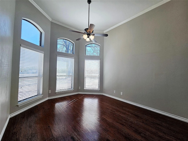 empty room featuring baseboards, ornamental molding, ceiling fan, and dark wood-style flooring