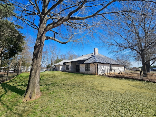 view of home's exterior with brick siding, a lawn, a chimney, and fence