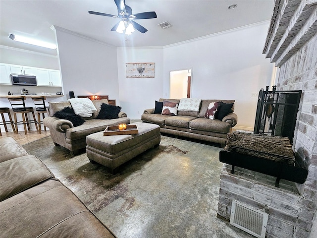 living area featuring ornamental molding, a fireplace, visible vents, and a ceiling fan