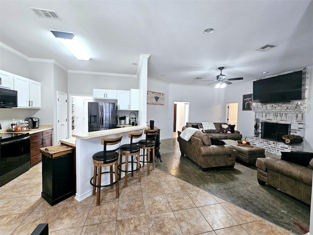 living room featuring crown molding, visible vents, a fireplace, and light tile patterned floors